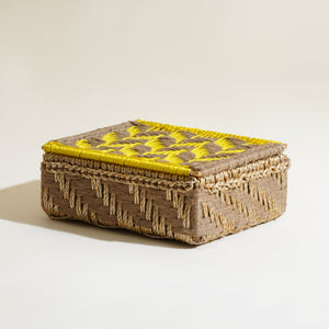 Woven box with yellow lid on a beige background
